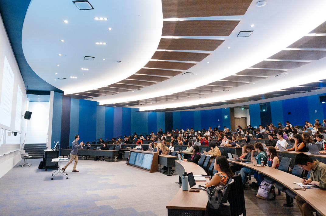 photo of seated students in a large classroom with professor at the front