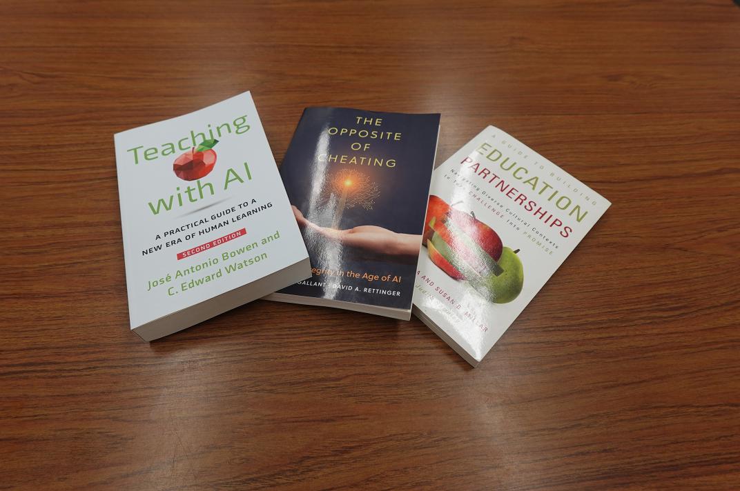 three books laid out on a brown wooden tabletop